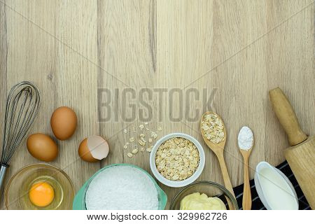 Tools And Ingredients For Baking Cake (flour, Butter, Eggs, Milk, Oatmeal) On Wooden Background. Top