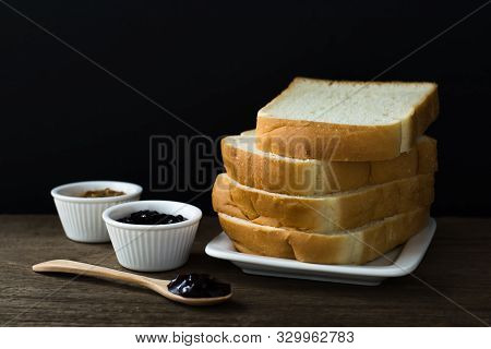 Toasted Bread Slices On A Single White Plate On Wooden Table With Black Background. Black Currant Ja