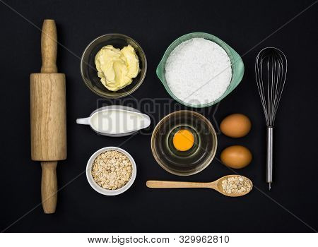 Tools And Ingredients  For The Dough (flour, Butter, Eggs, Milk, Oatmeal) On Black Background. Top V