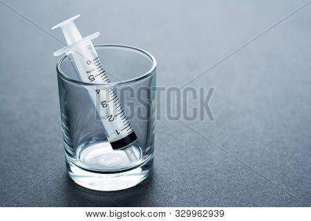 Empty Syringe Barrel In The Small Glass On The Black Background With Copy Space.