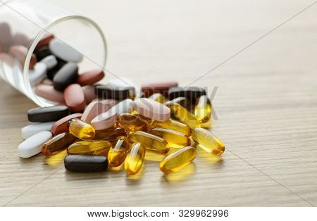 Fishoil Capsules And Multivitamin Supplements Out Of The Small Glass On The Wooden Table With Copy S