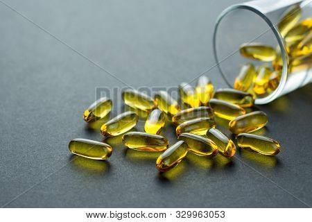 Fishoil Capsules Out Of The Small Glass On Black Background With Copy Space.