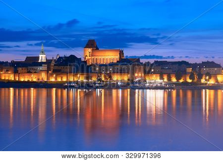 Skyline Of Torun Old Town In Poland, Unesco World Heritage Site, With Illumination. Old Walls Are Re