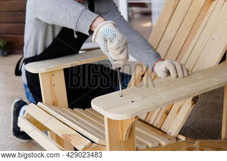 Professional Carpenter Assembling Wooden Adirondack Chair With Screwdriver. Manual Work And Do-it-yo