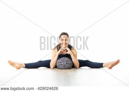 Restorative Yoga With A Bolster. Young Sporty Female Yoga Instructor In Bright White Yoga Studio, Ly