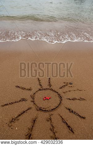 Figure Of A Red Plane And Painted The Sun On The Sand On The Coast. Rest And Tourism By Plane To The