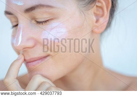 Closeup Portrait of a Nice Blond Female with Sun Cream on a Face. Closed Eyes. Using Spf Before Going to Beach. Health Care. Beauty Treatment at Spa.