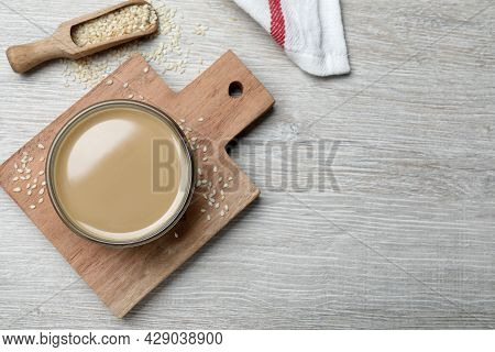 Tasty Sesame Paste, Seeds And Scoop On White Wooden Table, Flat Lay. Space For Text