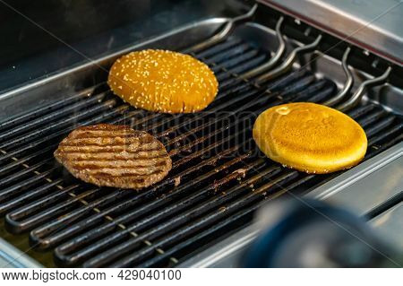Cooking Burgers At Restaurant. Close Up Of Chief Cooking Tasty Burger At Restaurant At The Grill. Un
