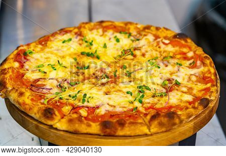 Fresh Pizza On Wooden Stand On The Table. Tasty Pizza With Tomato And Cheese On The Wooden Backgroun