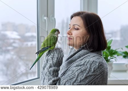 Middle Aged Woman And Parrot Together, Female Bird Owner Talking Looking At Green Quaker Pet