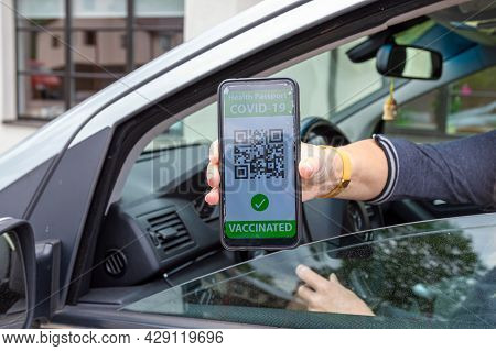 Driver In Car Shows A Digital Covid-19 Immunity Vaccine Passport, New Normal Travel Concept
