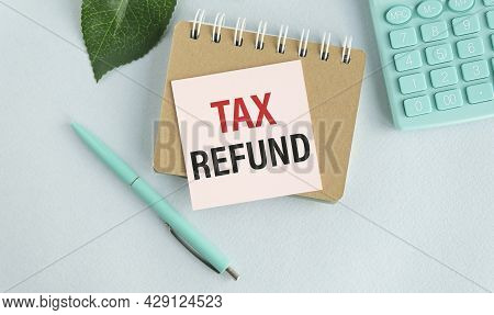 Notes Notebook With A Tax Refund With The Office Tools On Blue Background . Concept Tax Refund