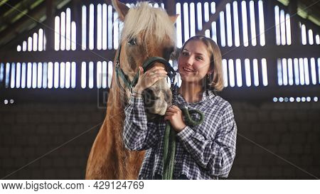 A Young Woman Strokes The Horses Snout Closely. High-quality Photo