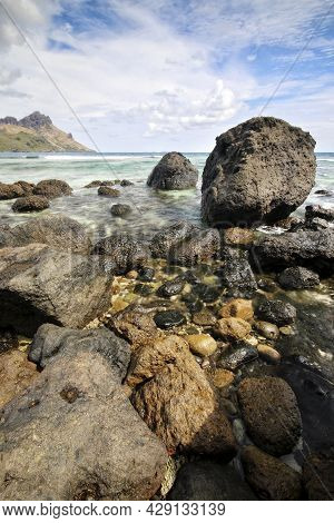 A Close Up Of A Rock Next To A Body Of Water