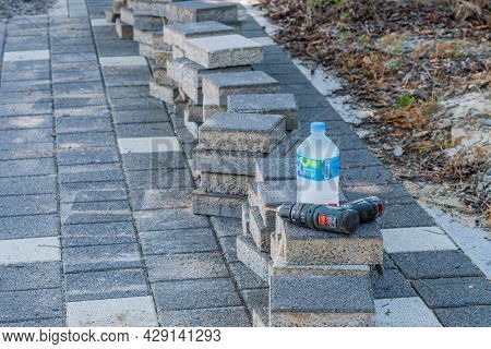 Cordless Power Drill On Stack Of Bricks Beside Bottle Of Mineral Water.