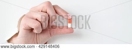 Female Hand Holds Medical Pill Through Hole Through White Paper