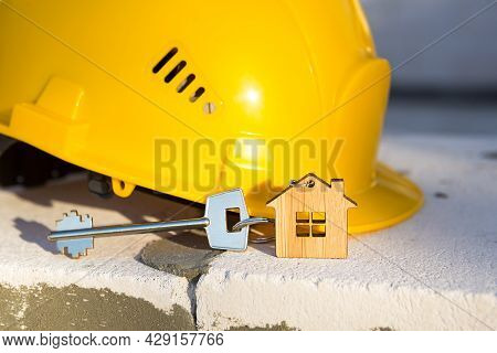 Construction Yellow Hardhat And Key To House On Window Of Housing Made Of Blocks Of Porous Concrete.