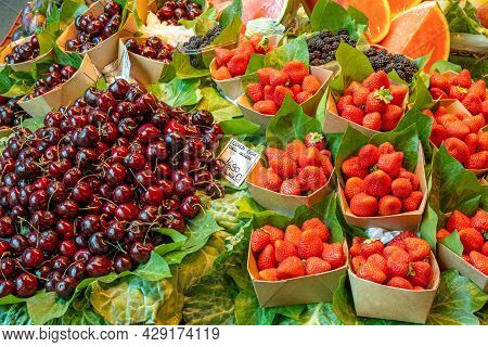 Cherries And Strawberries For Sale At A Market Stall