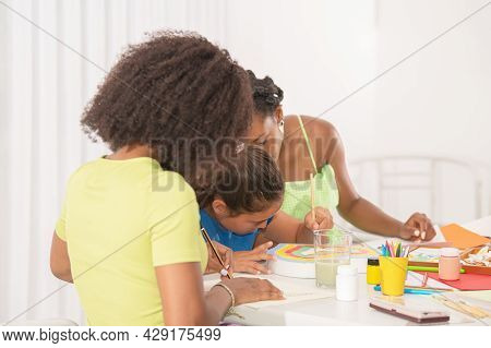 Side View Of A Little Girl Painting With Her Two Teachers In Art Class