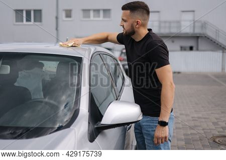 Man Wipes A Windshield Of His Car With A Rag In A Showroom At A Self-service Car Wash