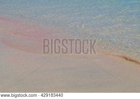 A Small Wave Of The Sea Covers The Pink Sand.