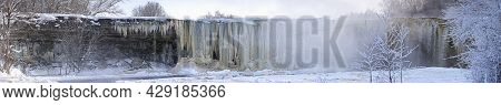 Frozen Beautiful Waterfall Jagala Under The Sunrise Lights In Winter, Reflection In River. Estonia.