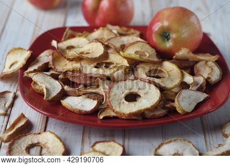 The Benefits Of Dried Fruits And Vegetables. Dried Apple Chips And Red Fresh Apples On A White Woode