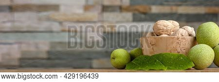 Walnut. Walnut Fruits Lie In A Wooden Saucer. Nearby Are Green Leaves And Unripe Walnut Fruits. Bann