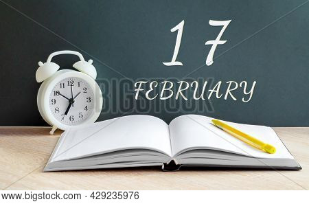 February 17. 17-th Day Of The Month, Calendar Date.a White Alarm Clock, An Open Notebook With Blank 