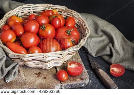 Fresh Red Tomatoes In Whicker Basket On Black Background