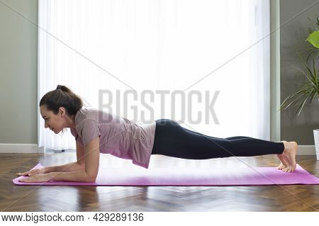 Young Sporty Woman Practicing Yoga, Doing Push Ups Exercise. Plank Pose And Workout. She Is Exercisi