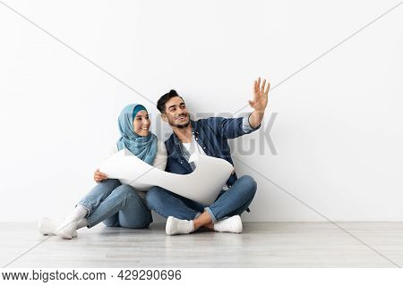Excited Young Arab Couple Working On New Home Interior