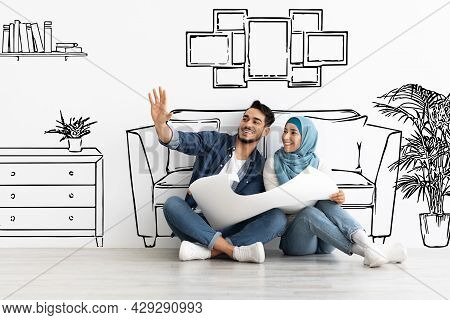 Happy Arab Husband And Wife In Hijab Planning House Interior