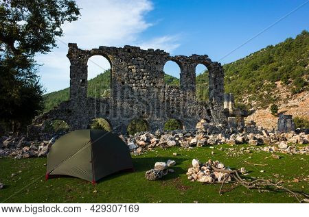 Camping next to Alakilise ruins along Lycian way hiking trail, Green tent stands near wall remains of Alakilise or Church of the Angel Gabriel in Lycia, near Finike and Demre, Antalya Province, Turkey