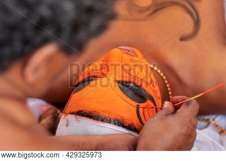 Payyanur, India - December 5, 2019: Hindu priest do make up for Theyyam performer during temple festival in Payyanur, Kerala, India. Theyyam is a popular ritual form of worship in Kerala