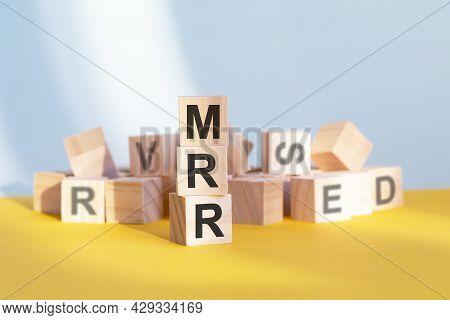 Wooden Cubes With Letters Mrr Arranged In A Vertical Pyramid, Grey And Yellow Background, Business C