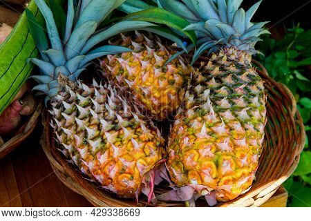 Fresh Ripe Yellow And Green Pineapples In A Wicker Basket At The Market