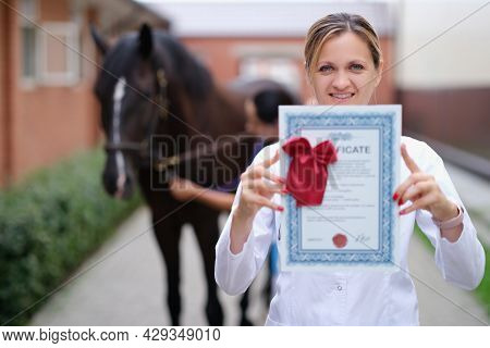 Woman Veterinarian Holding Training Certificate On Horse Background