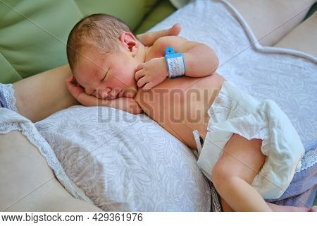 A Mother Is Holding A Newborn Baby In Her Arms, With A Maternity Hospital Bracelet On Her Arm. A New