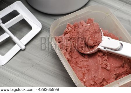 Homemade Cherry Ice Cream In A Plastic Container On The Table With An Ice Cream Spoon And An Ice Cre