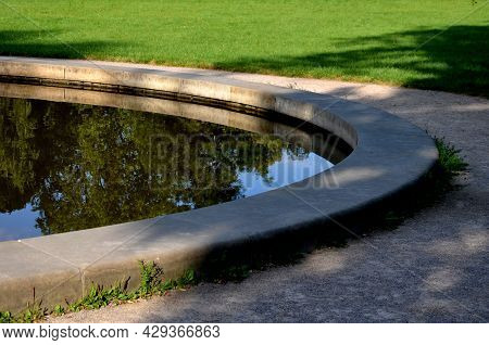 Edge Of A Stone Sandstone Circular Fountain In The Park. Built Of Sandstone Filled With Water. Lined