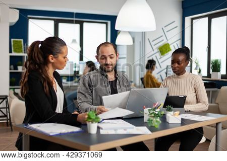Happy Diverse Businesspeople Analysing Great Annual Financial Reports Sitting At Desk Using Laptop. 
