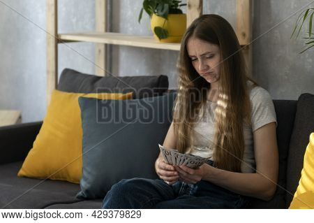 Young Woman Is Counting Money And Is Saddened By The Expenses. Girl Recounts Her Salary. Low Salary.