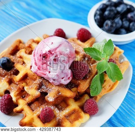 Belgian waffles with fresh berries and ice cream over wooden background. Top view.