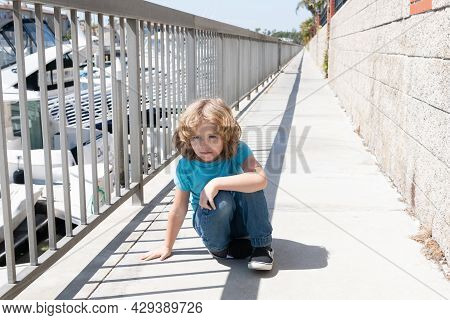 Boy Child Take Short Break Hunkering Down On Promenade, Rest