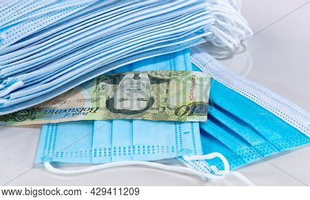 Face Masks And Pula Of Botswana On White Background. Face Mask The New World Currency. Corona Virus 