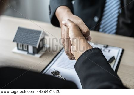 Salesperson And Customer Shake Hands After Signing The Contract, The Salesperson Explains The Detail