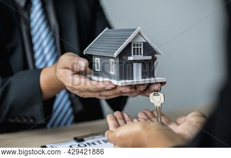 The Salesperson Handed The Small Gray Model Of The House And The House Keys To The Customer As A Sig