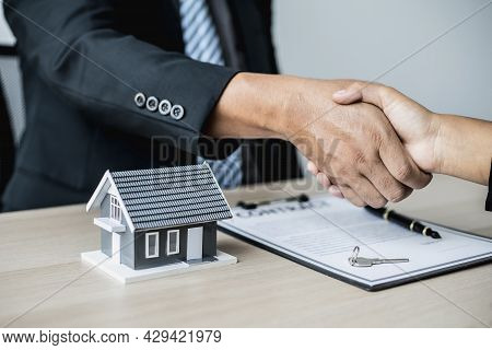 Salesperson And Customer Shake Hands After Signing The Contract, The Salesperson Explains The Detail